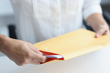 Woman client reads news in paper envelope at home desk