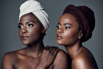 African Queens. Studio shot of two beautiful young women posing against a grey background.