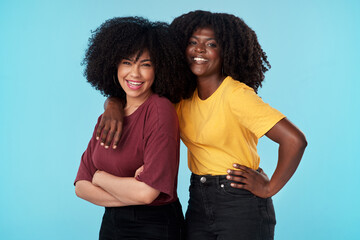 Wall Mural - Friends dont let friends stand alone. Studio shot of two young women embracing each other against a blue background.