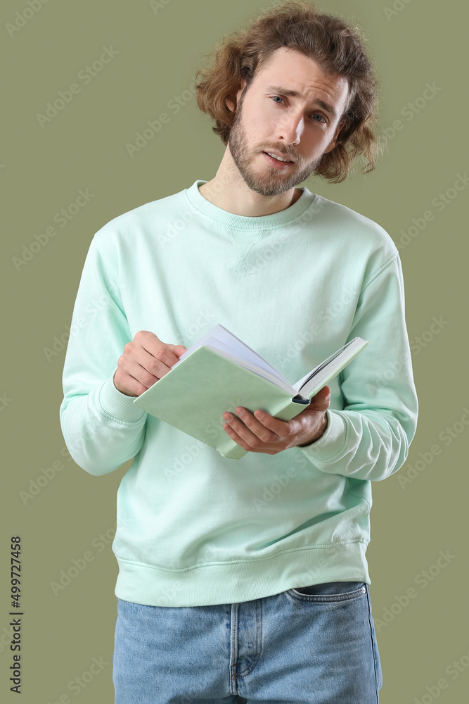 Handsome man reading book on green background