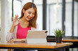 © David - Portrait of a beautiful young and intelligent-looking Japanese Asian woman student wearing a white shirt and pink tracker smiling as she works on her laptop in a university classroom.