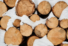Close-up Of Dry Chopped Firewood Forming Woodpile Covered With Snow That Can Be Used As Background For Your Advertisement