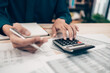 © Charnchai saeheng - Investors working on desk office and using a calculator to calculate balance, projit, currency and cost. Accounting and  Financial concept.