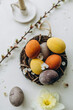 Easter eggs in a wicker nest and decorated with white petals. easter eggs and yellow narcissus flower. painted easter eggs top view. chicken eggs dyed with natural dyes.