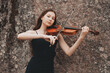 © Fotograf - Asian girl plays the violin on the background of a stone wall