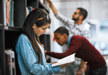 Aufkleber - I cant put this book down. Shot of a group young students standing in a library picking out books to read.