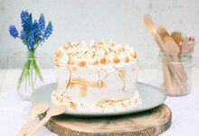 Close Up Of Meringue And Lemon Curd Cake Next To A Vase With Grape Hyacinth Flowers