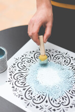 Person Using A Dabber With Acrylic Paint On A Mandala Stencil