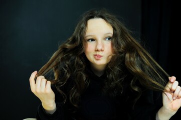 Wall Mural - a teenager in a black hoodie in a dark room close-up of face and emotion dissatisfied and serious. High quality photo