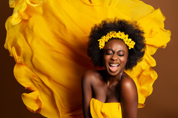 Wall Mural - Cheerful Expression Afro American Model over Yellow Silk Flying Fabric Background. Happy Smiling Young Dark Skinned Woman Singing. Pleased Excited fashion Girl laughing