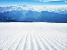Snowy Groomed Slope With Velvet Lines In Ski Resort At Mountains Background