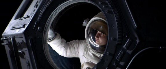 Wall Mural - portrait of caucasian female astronaut flying towards spaceship cupola window. space exploration, ma