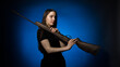 © Sergey - a young girl with long flowing hair in a black T-shirt with a gun on her shoulder on a dark background