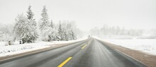Empty Highway (asphalt Road) Through The Snow-covered Forest And Field. USA. Nature, Christmas Vacations, Remote Places, Winter Tires, Dangerous Driving Concept