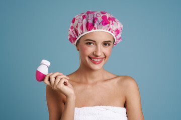 Wall Mural - Young woman wearing shower cap posing with facial massager