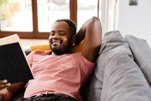 Bristle Black Man Reading Book While Resting On Sofa