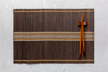 Wall Mural - Two chopsticks and bamboo mat on cement background. Top view, copy space