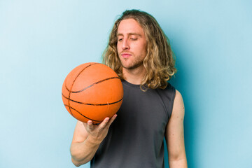 Wall Mural - Young caucasian man playing basketball isolated on blue background