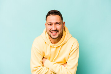 Wall Mural - Young hispanic man isolated on blue background laughing and having fun.