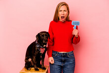 Young Caucasian Woman Combing The Dog Isolated On Pink Background Screaming Very Angry And Aggressive.