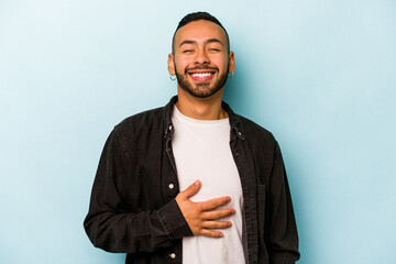 Young hispanic man isolated on blue background touches tummy, smiles gently, eating and satisfaction concept.