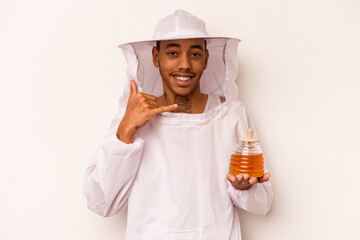 Young African American beekeeper isolated on white background showing a mobile phone call gesture with fingers.