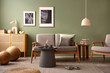 Elegant composition of living room interior. Modern scandi sofa, design pillows, side table, rattan commode and creative personal accessories. Sage green wall. Template. Copy space.