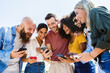 © Xavier Lorenzo - Young group of happy people smiling while using mobile phone together - Smiling multiracial friends standing outdoors in the park holding cellphone - Technology, youth and social media concept