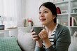 © PR Image Factory - pretty asian lady holding hot drink is beaming with happiness. portrait of korean young lady is enjoying her coffee on weekend morning.