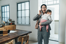 Asian Female Ceo Carrying Toddler Just Getting Home Is Receiving Emergent Phone Call From Company. Chinese Businesswoman With Baby Opening Mouth Wide Is Surprised At A Bad News She Hears On Phone.