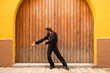 man dancing flamenco with black shirt and red roses, on a background of a wooden door, doing different postures while dancing. Flamenco dance concept cultural heritage of humanity. Feel de passion.