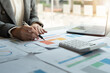 © Natee Meepian - Businesswoman of bookkeeper working new plan financial graph data on laptop and doing finances, calculate investment and business strategy.