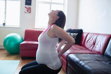 Pregnant Woman Stretching Back On Living Room Floor