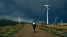 Woman Running In Stormy Weather Near Windmill