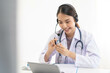 © KMPZZZ - Doctor or physician wearing white coat, stethoscope using headset, consulting health by telehealth online for speaking video call consultation on tablet. Telemedicine by medical for distance patient.
