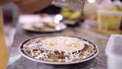 Wall Mural - Unrecognizable person grating cheese on meal with eggs and nachos