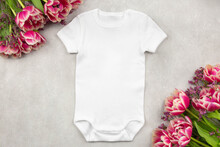 White Baby Girl Or Boy Bodysuit Mockup Flat Lay With Tulip Flowers On Gray Concrete Background. Design Onesie Template, Print Presentation Mock Up. Top View. 
