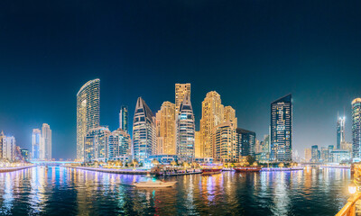 Wall Mural - Dubai Marina Port, UAE, United Arab Emirates - Beautiful Night view of high-rise buildings of residential district in Dubai Marina And Tourist Boat, Sightseeing Boat Sailing On Dubai Marina. Panorama