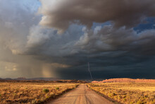 Dirt Road With Dark, Ominous Storm Clouds And Lightning