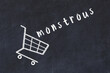 Chalk drawing of shopping cart and word monstrous on black chalboard. Concept of globalization and mass consuming