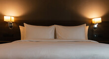 White Pillows And Blanket In Bed With Light From Lamps At Night
