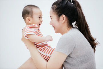 Asian mom enjoy with baby adorable on the bed is smiling and happy. Happy family. Unconditional love infant baby.