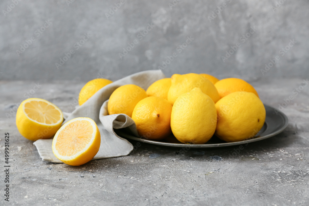 Plate of fresh lemons on grey table