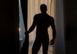 © Volodymyr - Sexy gay silhouette. Sexy naked muscular man next to window. Shirtless man covered with shadow from window.