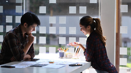 Wall Mural - two designers sitting in bright modern office and discussing about application development for mobil