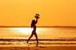 © Spotmatik - Asian female playing ball by ocean at sunset