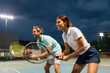 © NDABCREATIVITY - Tennis sport people concept. Mixed doubles player hitting tennis ball with partner standing near net