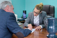 Female Funeral Director Completing Paperwork With Senior Man