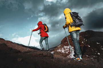 couple of active young people hikers with backpack and trekking poles climbing on the mount etna in 