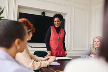 Portrait Of Cheerful Mature Black Businesswoman Listening To Female Colleagues In Meeting Room And Smiling